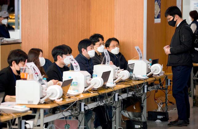South Korea s early voting for the April 15 general elections, Apr 10, 2020 : Election officials (L) check voters identification at a polling station on the first day of the two-day early voting for the April 15 general elections in Seoul, South Korea. To prevent COVID-19 coronavirus infection, voters were asked to stand at least 1 meter away from each other at polling stations. They were advised to wear face masks and were allowed to cast ballots after using hand sanitizers and putting on gloves. The quadrennial elections will fill the 300-seat unicameral National Assembly of South Korea.  (125234303)