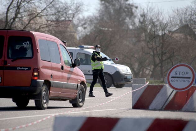 ZOLOCHIV, UKRAINE - APRIL 10, 2020 - A police officer in a face mask orders a driver to pull up at a roadblock set up on the border with Ternopil Region during the COVID-19 outbreak, Zolochiv, Lviv Region, western Ukraine. Roadblock in Zolochiv  Copyright: xMARKIIANxLYSEIKOx