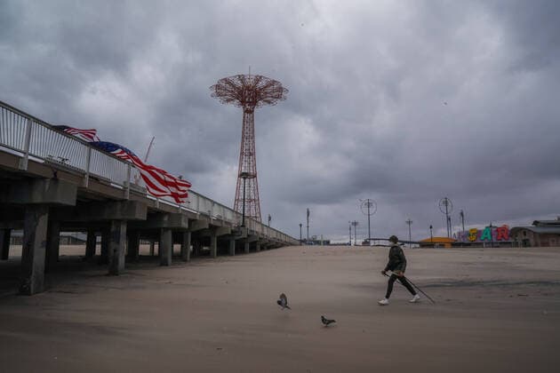 April 10, 2020, New York, NY, USA: A woman walks past American flags blowing in the wind off a pier in the Coney Island section of the Borough of Brooklyn on April 10, 2020 in New York. New York USA - ZUMAb148 20200410_zap_b148_133 Copyright: xBryanxSmithx