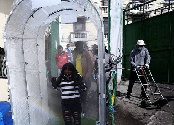 A woman with a facial mask enters through a disinfection tunnel in the San Roque market, one of the largest in Quito, Ecuador, 10 April 2020. Quito citizens buy there the ingredients of the famous Fanesca, the traditional stew of Easter in Ecuador, which is usually served on Good Friday. Fanesca, the Ecuadorian dish on Good Friday, stays at home due to COVID-19 !ACHTUNG: NUR REDAKTIONELLE NUTZUNG!  Copyright: xJosexJacomex AME1808 20200411-637221600184826266