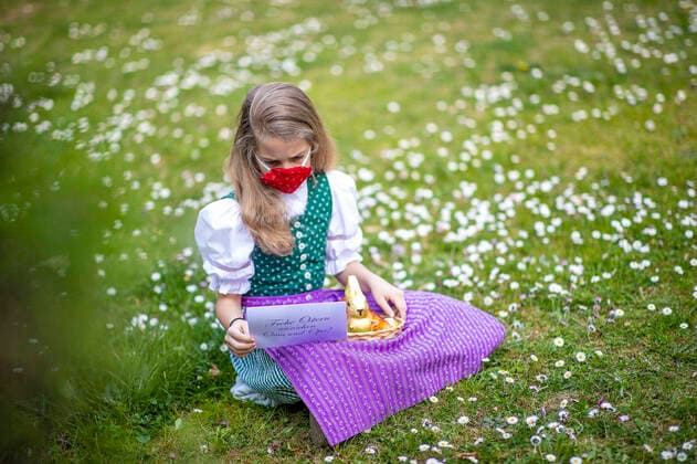 Graz THEME IMAGE A girl in traditional costume with NMS mask with an Easter nest and chocolate bunnies on a flower meadow, taken on 10 April 2020, in Graz a girl in traditional austrian dress and a face mask is seeking for an easter present in a flower meadow on 10 April 2020  EP_ies