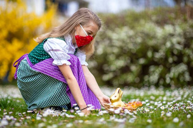 Graz THEME IMAGE A girl in traditional costume with NMS mask with an Easter nest and chocolate bunnies on a flower meadow, taken on 10 April 2020, in Graz a girl in traditional austrian dress and a face mask is seeking for an easter present in a flower meadow on 10 April 2020  EP_ies