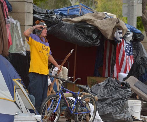 Homeless veteran salutes at an encampment, adjacent to the West Los Angeles VA Medical Center during the coronavirus pandemic in Los Angeles on Friday, April 10, 2020.  LAP2020041015 JIMxRUYMEN