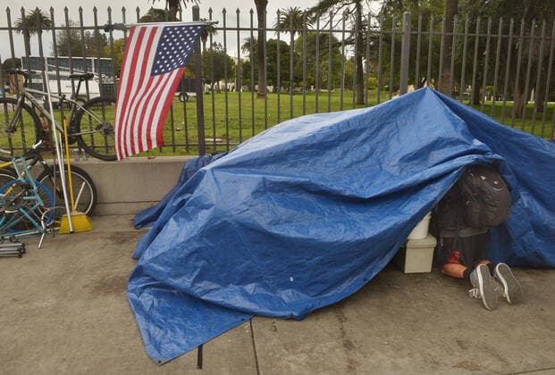 A homeless veteran makes room in his tent at an encampment, adjacent to the West Los Angeles VA Medical Center during the coronavirus pandemic in Los Angeles on Friday, April 10, 2020.  LAP2020041025 JIMxRUYMEN