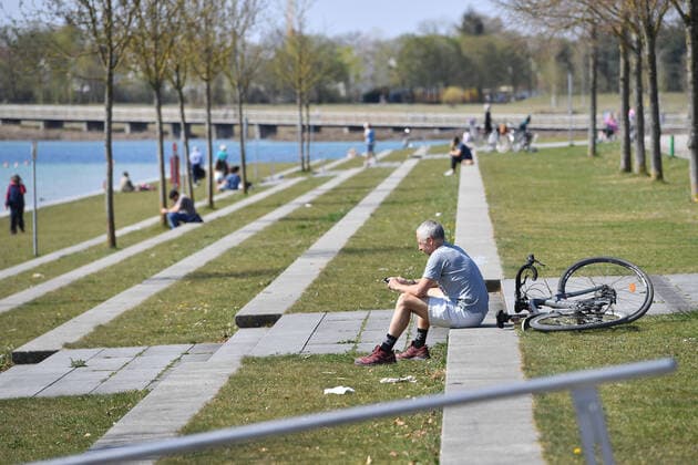 Easter in times of the Corona Pandemic Public life on 11 04 2020 People sit alone or in pairs on the shore of Lake Buga in Riemer Park in Munich The spring weather drives the population to fresh air, always with the necessary distance because of an infection with the corona virus