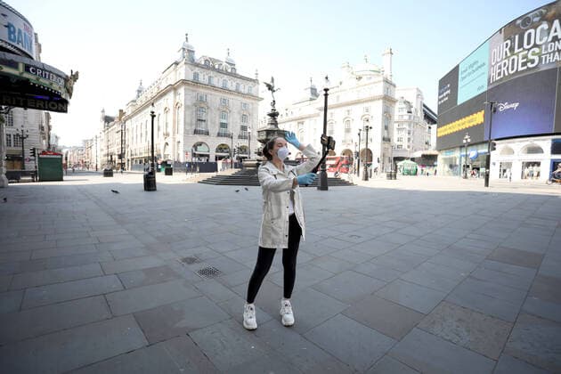 Day Nineteen of Lockdown in London. A lady poses for a selfie in almost deserted Piccadilly Circus in London on Easter Saturday. It is the first public holiday of the year, and many people enjoy the long weekend by going out and about or on holiday, but this year the country is on lockdown due to the COVID-19 Coronavirus pandemic. People are not allowed to leave home except for minimal food shopping, medical treatment, exercise - once a day, and essential work. COVID-19 Coronavirus lockdown, London, UK, on April 11, 2020 