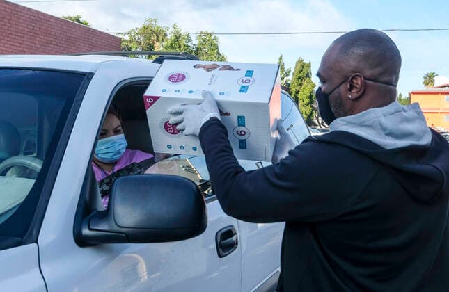 April 11, 2020, Los Angeles, California, U.S: A staff hands a box of diapers to a driver during a drive thru grab-and-go distribution of diapers to assist families in need during the COVID-19 outbreak on Saturday April 11, 2020, in Los Angeles. Los Angeles U.S. - ZUMAc68_ 20200411_zaf_c68_001 Copyright: xRingoxChiux