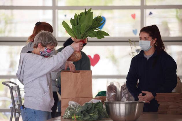 April 11, 2020, Bloomington, Indiana, United States: Workers wearing face masks prepare internet orders for customers of Bloomington Community Farmers Market where food is being distributed in a drive-thru arrangement at the Switchyard Pavilion. Bloomington United States - ZUMAs197 20200411_zaa_s197_185 Copyright: xJeremyxHoganx