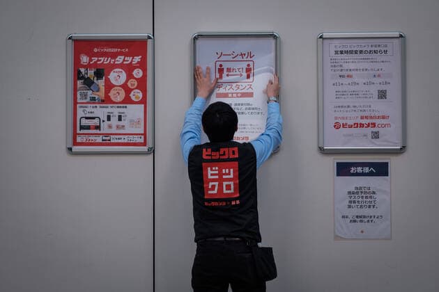 A Uniqlo staff put on a wall a poster about social distancing in Shinjuku East area in Tokyo, Japan, 11 April 2020. Japanese Prime Minister Shinzo Abe declared a state of emergency for at least one month amid an increase of coronavirus and COVID-19 infection cases. April 11, 2020  (125267608)