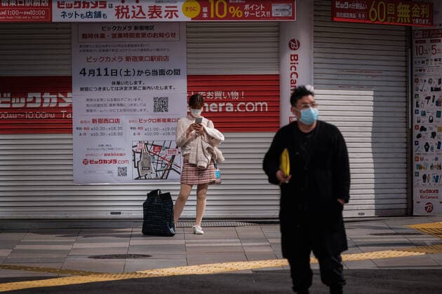 A girl wearing a mask use her phone in front of a closed shop in Shinjuku East area in Tokyo, Japan, 11 April 2020. Japanese Prime Minister Shinzo Abe declared a state of emergency for at least one month amid an increase of coronavirus and COVID-19 infection cases. April 11, 2020  (125267609)