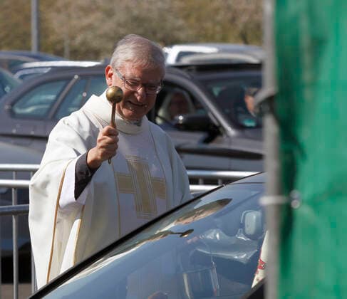 12 04 2020, Catholic Easter Mass at the drive-in cinema in Düsseldorf, Düsseldorf city dean Frank Heidkamp blesses the cars as they leave the grounds after the service 12 04 2020, Catholic Easter Mass at the drive-in cinema in Düsseldorf 12 04 2020, Catholic Easter Mass at the drive-in cinema in Düsseldorf