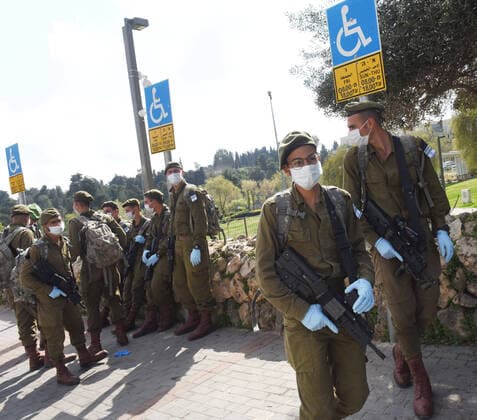 Israeli soldiers wear masks and gloves, as protection against the coronavirus, before being deployed to lockdown religious neighborhoods, in Jerusalem, on Sunday, April 12, 2020. The Israeli government deployed a 1,000 police to enforce a full closure on Jewish religious neighborhoods with the highest rate of coronavirus in Jerusalem. According to the Health Ministry about 75 percent of the infected in Jerusalem live in the Ultra-Orthodox neighborhoods.  JER2020041221 DEBBIExHILL