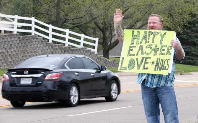 Donald Newner waves to passing cars, holding a sign with his Easter message, as he stands on a street corner in St. Charles, Missouri on Sunday, April 12, 2020.  SLP2020041209 BILLxGREENBLATT