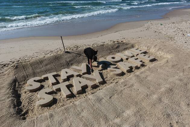 (200412) -- GAZA, April 12, 2020 (Xinhua) -- A Palestinian artist carves words STAY HOME STAY SAFE with sand on a beach in Gaza City, on April 12, 2020. Palestine said on Sunday that the total number of COVID-19 cases in the country has reached 290. (Photo by Rizek Abdeljawad Xinhua) MIDEAST-GAZA CITY-COVID-19-SAND ART 