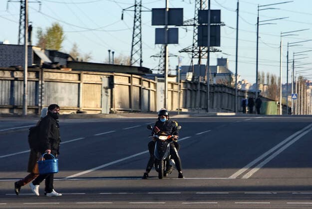KYIV, UKRAINE - APRIL 12, 2020 - A biker in a face mask waits for pedestrians to cross a street during quarantine amid the COVID-19 pandemic, Kyiv, capital of Ukraine. Daily life of Kyiv in quarantine  Copyright: xOvsyannikovaxYuliax