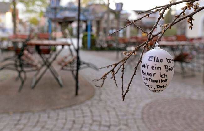 13 04 2020, Shops and restaurants close due to Corona Virus Pandemic in Bad Wörishofen, Tables and chairs in a beer garden currently without guests Guests have hung up Easter eggs with handwritten greetings Elke bring me a beer before I wilt 13 04 2020, Closed restaurants due to Corona Virus 13 04 2020, Closed restaurants due to Corona Virus