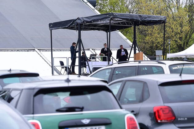 Easter service in the drive-in cinema on 13 04 2020 in Düsseldorf Pastor Heinrich Fucks leads through the Protestant service The altar is located on a truck positioned in front of the drive-in cinema screen The sermon of the pastor is transmitted via the drive-in cinemas audio system to the radios of the participating vehicles The Düsseldorf drive-in cinema was built in response xRx