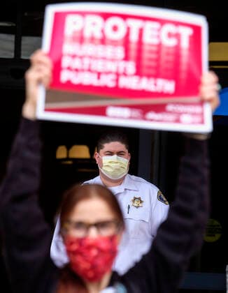 April 13, 2020, Los Angeles, California, U.S: A security man warring a mask looks on as nurses and healthcare workers in a protest for the lack of personal protective equipment at UCLA Medical Center in Santa Monica, California, Monday April 13, 2020. Los Angeles U.S. - ZUMAc68_ 20200413_zaf_c68_007 Copyright: xRingoxChiux