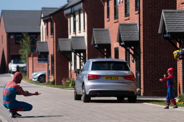 (200414) -- MANCHESTER, April 14, 2020 (Xinhua) -- Jason Baird, who runs a martial arts academy in South Manchester, dressed up as Spider-Man, interacts with a child with social distancing amid the COVID-19 outbreak in Manchester, Britain on April 13, 2020. (Photo by Jon Super Xinhua) BRITAIN-MANCHESTER-COVID-19-SPIDER-MAN 