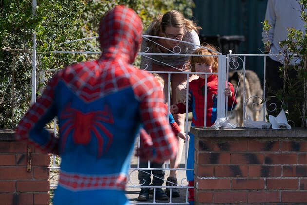 (200414) -- MANCHESTER, April 14, 2020 (Xinhua) -- Jason Baird, who runs a martial arts academy in South Manchester, dressed up as Spider-Man, talks with a child with social distancing amid the COVID-19 outbreak in Manchester, Britain on April 13, 2020. (Photo by Jon Super Xinhua) BRITAIN-MANCHESTER-COVID-19-SPIDER-MAN 