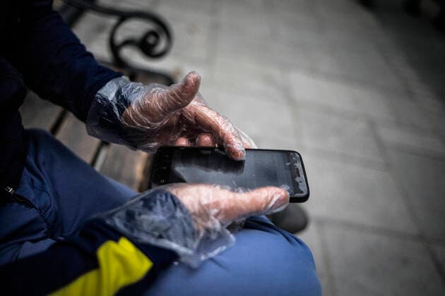 (200414) -- TEHRAN, April 14, 2020 -- A man wearing gloves works with his mobile phone on a street in Tehran, Iran, April 13, 2020. Iran registered 1,574 new COVID-19 cases over the past 24 hours, bringing the total number of confirmed cases to 74,877, according to Iran s health ministry on Tuesday. (Photo by Xinhua) IRAN-TEHRAN-COVID-19-CASES AhmadxHalabisaz 