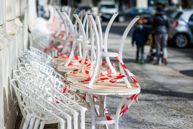 Corona Life The white tables and chairs are piling up, tied up with red and white flutterband, in front of a restaurant in Mommsenstrasse, Berlin Charlottenburg Corona Coronavirus Shutdown Restrictions Dealing with Corona Corona Everyday life Restaurants OPEN FOR TAKE AWAY Take away Tables and chairs are piling up Tables and chairs Chairs Flutterband Berlin Berlin Deu