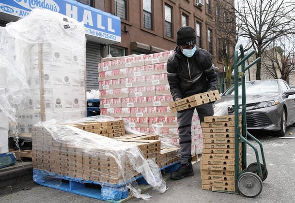 A worker puts cartons of food on to a hand truck when New York City Mayor Bill de Blasio visits The Campaign Against Hunger food pantry in New York City on Tuesday, April 14, 2020. As of today nearly 285,000 have been infected and more than 14,000 people have died in NY, NJ and CT. There are signs however that the curve is flattening.  NYP20200414105 JOHNxANGELILLO