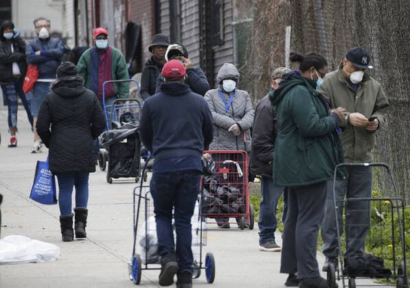 People wait on line for food wearing protective face masks while New York Mayor Bill de Blasio speaks to workers at The Campaign Against Hunger food pantry in New York City on Tuesday, April 14, 2020. As of today nearly 285,000 have been infected and more than 14,000 people have died in NY, NJ and CT. There are signs however that the curve is flattening.  NYP20200414114 JOHNxANGELILLO