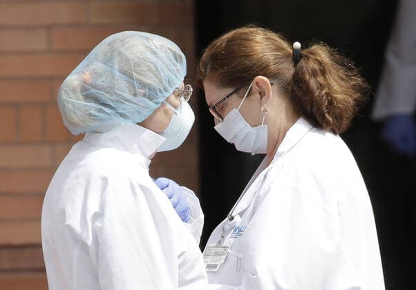 Healthcare workers wearing protective face masks and medical clothes stand outside of an entrance to Wyckoff Heights Medical Center in New York City on Tuesday, April 14, 2020. As of today nearly 285,000 have been infected with Coronavirus and more than 14,000 people have died in NY, NJ and CT. There are signs however that the curve is flattening.  NYP20200414127 JOHNxANGELILLO
