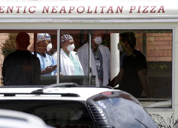Healthcare workers wearing protective face masks and medical clothes stand outside of an entrance to Wyckoff Heights Medical Center in New York City on Tuesday, April 14, 2020. As of today nearly 285,000 have been infected with Coronavirus and more than 14,000 people have died in NY, NJ and CT. There are signs however that the curve is flattening.  NYP20200414123 JOHNxANGELILLO