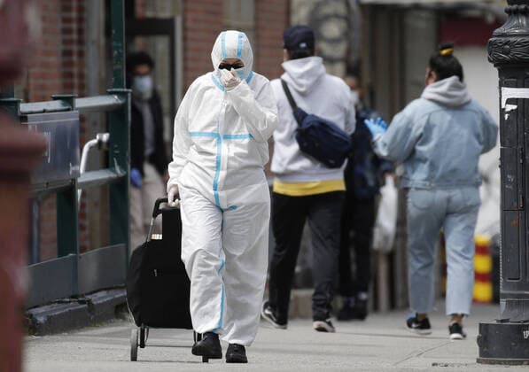 A pedestrian covered head to toe in protective clothes crosses walks on the sidewalk near Wyckoff Heights Medical Center in New York City on Tuesday, April 14, 2020. As of today nearly 285,000 have been infected with Coronavirus and more than 14,000 people have died in NY, NJ and CT. There are signs however that the curve is flattening.  NYP20200414124 JOHNxANGELILLO