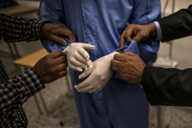 (200415) -- TRIPOLI, April 15, 2020 (Xinhua) -- Libyan medical staff help a medical worker to try on a protective suit in a fashion school which was turned into a workshop producing protective gears in Tripoli, Libya, on April 14, 2020. The Libyan National Center for Disease Control on Tuesday announced nine new COVID-19 cases, bringing the total number of confirmed cases in the country to 35. (Photo by Amru Salahuddien Xinhua) LIBYA-TRIPOLI-COVID-19-PROTECTIVE WORKSHOP 