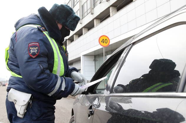 MOSCOW, RUSSIA - APRIL 15, 2020: A traffic police officer carries out an ID check on Volokolamskoye Shosse Motorway during the pandemic of the novel coronavirus disease (COVID-19). Traffic police have set up checkpoints around the city to stop vehicles and see if drivers have permission to travel during the lockdown. On 13 April 2020, the Moscow government introduced a digital permit system aimed at further restricting movement. Under the new scheme, which becomes mandatory from 15 April, people need to apply for permits to travel on a vehicle or public transport around the city. Earlier, on 11 April, the Moscow government restricted vehicles registered outside Moscow Region from entering the Russian capital. Since 31 March 2020, Moscow has been on lockdown. As of 15 April 2020, Russia has reported more than 21,100 confirmed cases of the TS0D5C64