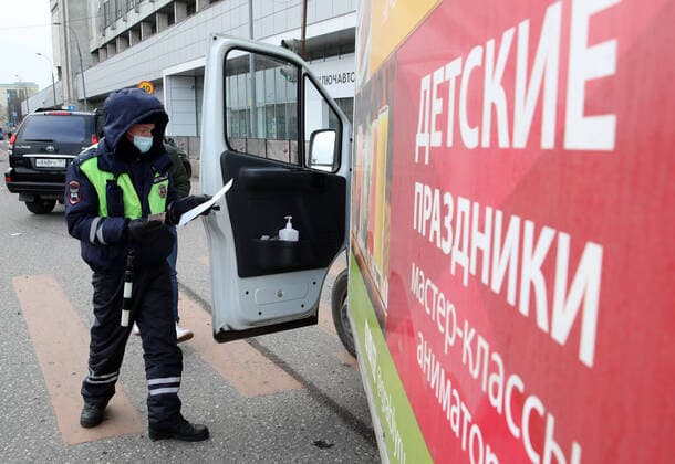 MOSCOW, RUSSIA - APRIL 15, 2020: A traffic police officer in a face mask carries out an ID check on Volokolamskoye Shosse Motorway during the pandemic of the novel coronavirus disease (COVID-19). Traffic police have set up checkpoints around the city to stop vehicles and see if drivers have permission to travel during the lockdown. On 13 April 2020, the Moscow government introduced a digital permit system aimed at further restricting movement. Under the new scheme, which becomes mandatory from 15 April, people need to apply for permits to travel on a vehicle or public transport around the city. Earlier, on 11 April, the Moscow government restricted vehicles registered outside Moscow Region from entering the Russian capital. Since 31 March 2020, Moscow has been on lockdown. As of 15 April 2020, Russia has reported more than 21,100 confirme TS0D5C65