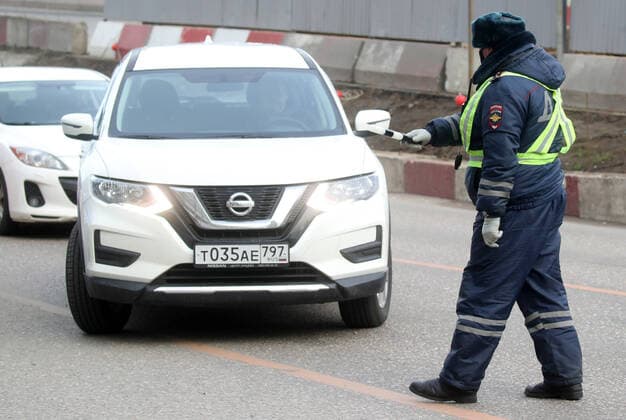 MOSCOW, RUSSIA - APRIL 15, 2020: A traffic police officer carries out ID checks on Volokolamskoye Shosse Motorway at the entrance to Moscow during the pandemic of the novel coronavirus disease (COVID-19). Traffic police have set up checkpoints around the city to stop vehicles and see if drivers have permission to travel during the lockdown. On 13 April 2020, the Moscow government introduced a digital permit system aimed at further restricting movement. Under the new scheme, which becomes mandatory from 15 April, people need to apply for permits to travel on a vehicle or public transport around the city. Earlier, on 11 April, the Moscow government restricted vehicles registered outside Moscow Region from entering the Russian capital. Since 30 March 2020, Moscow has been on lockdown. As of 15 April 2020, Russia has reported more than 21,100 TS0D5C69