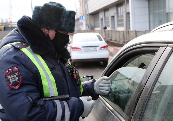 MOSCOW, RUSSIA - APRIL 15, 2020: A traffic police officer in a face mask carries out an ID check on Volokolamskoye Shosse Motorway during the pandemic of the novel coronavirus disease (COVID-19). Traffic police have set up checkpoints around the city to stop vehicles and see if drivers have permission to travel during the lockdown. On 13 April 2020, the Moscow government introduced a digital permit system aimed at further restricting movement. Under the new scheme, which becomes mandatory from 15 April, people need to apply for permits to travel on a vehicle or public transport around the city. Earlier, on 11 April, the Moscow government restricted vehicles registered outside Moscow Region from entering the Russian capital. Since 30 March 2020, Moscow has been on lockdown. As of 15 April 2020, Russia has reported more than 21,100 confirme TS0D5C78