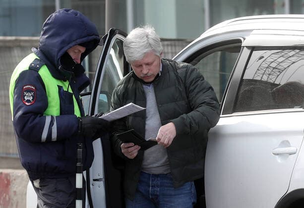 MOSCOW, RUSSIA - APRIL 15, 2020: A traffic police officer carries out an ID check on Volokolamskoye Shosse Motorway during the pandemic of the novel coronavirus disease (COVID-19). Traffic police have set up checkpoints around the city to stop vehicles and see if drivers have permission to travel during the lockdown. On 13 April 2020, the Moscow government introduced a digital permit system aimed at further restricting movement. Under the new scheme, which becomes mandatory from 15 April, people need to apply for permits to travel on a vehicle or public transport around the city. Earlier, on 11 April, the Moscow government restricted vehicles registered outside Moscow Region from entering the Russian capital. Since 30 March 2020, Moscow has been on lockdown. As of 15 April 2020, Russia has reported more than 21,100 confirmed cases of the TS0D5C79