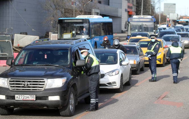MOSCOW, RUSSIA - APRIL 15, 2020: Traffic police officers in face masks carry out an ID check on Volokolamskoye Shosse Motorway during the pandemic of the novel coronavirus disease (COVID-19). Traffic police have set up checkpoints around the city to stop vehicles and see if drivers have permission to travel during the lockdown. On 13 April 2020, the Moscow government introduced a digital permit system aimed at further restricting movement. Under the new scheme, which becomes mandatory from 15 April, people need to apply for permits to travel on a vehicle or public transport around the city. Earlier, on 11 April, the Moscow government restricted vehicles registered outside Moscow Region from entering the Russian capital. Since 30 March 2020, Moscow has been on lockdown. As of 15 April 2020, Russia has reported more than 21,100 confirmed ca TS0D5C98