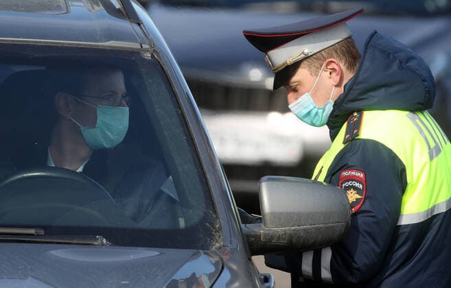 MOSCOW, RUSSIA - APRIL 15, 2020: A traffic police officer in a face mask carries out an ID check on Volokolamskoye Shosse Motorway during the pandemic of the novel coronavirus disease (COVID-19). Traffic police have set up checkpoints around the city to stop vehicles and see if drivers have permission to travel during the lockdown. On 13 April 2020, the Moscow government introduced a digital permit system aimed at further restricting movement. Under the new scheme, which becomes mandatory from 15 April, people need to apply for permits to travel on a vehicle or public transport around the city. Earlier, on 11 April, the Moscow government restricted vehicles registered outside Moscow Region from entering the Russian capital. Since 30 March 2020, Moscow has been on lockdown. As of 15 April 2020, Russia has reported more than 21,100 confirme TS0D5C9C