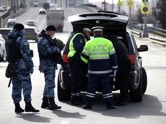 MOSCOW, RUSSIA - APRIL 15, 2020: Armed Rosgvardia OMON officers and traffic police officers in face masks carry out an ID check on Leningradskoye Shosse Motorway at the entrance to Moscow during the pandemic of the novel coronavirus disease (COVID-19). Traffic police have set up checkpoints around the city to stop vehicles and see if drivers have permission to travel during the lockdown. On 13 April 2020, the Moscow government introduced a digital permit system aimed at further restricting movement. Under the new scheme, which becomes mandatory from 15 April, people need to apply for permits to travel on a vehicle or public transport around the city. Earlier, on 11 April, the Moscow government restricted vehicles registered outside Moscow Region from entering the Russian capital. Since 30 March 2020, Moscow has been on lockdown. As of 15  TS0D5CAA