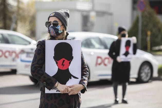 Queue Protest women s strike in Poland Protesters hold placards and wear face masks broaching the issue of Poland s restrictive abortion ban and penalties for sex education during a so called Queue Protest or Black Protest on April 14, 2020 in Poznan, Poland, Protesters lined up in front of a store so as not to violate the provisions related to the coronavirus pandemic. EN_01424678_0001 