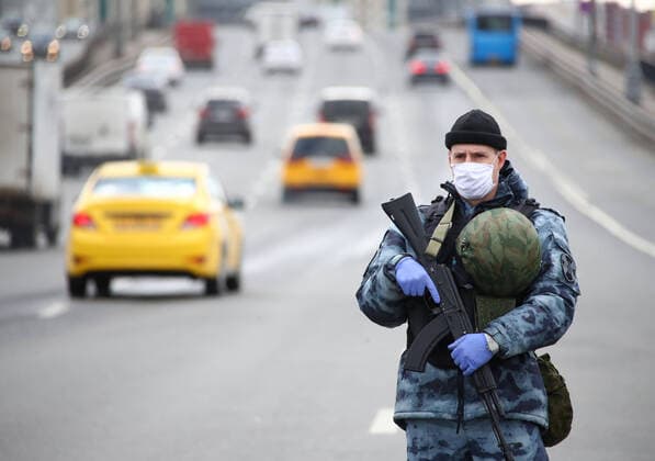 MOSCOW, RUSSIA - APRIL 15, 2020: An armed Rosgvardia OMON officer a face mask stands guard on Leningradskoye Shosse Motorway at the entrance to Moscow during the pandemic of the novel coronavirus disease (COVID-19). Traffic police have set up checkpoints around the city to stop vehicles and see if drivers have permission to travel during the lockdown. On 13 April 2020, the Moscow government introduced a digital permit system aimed at further restricting movement. Under the new scheme, which becomes mandatory from 15 April, people need to apply for permits to travel on a vehicle or public transport around the city. Earlier, on 11 April, the Moscow government restricted vehicles registered outside Moscow Region from entering the Russian capital. Since 30 March 2020, Moscow has been on lockdown. As of 15 April 2020, Russia has reported more  TS0D5CDF