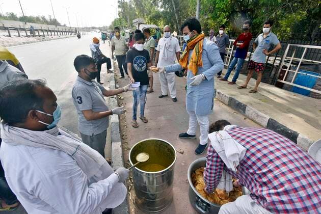NEW DELHI, INDIA - APRIL 15: Baba Gorakhnath Dhuna Ashram workers distributing food to slum people at NH 24 near mother dairy, on day twenty two of the 21-day nationwide lockdown on April 15, 2020 in New Delhi, India. (Photo by Sanjeev Verma Hindustan Times) Government Provide Food To Homeless And Poor Amid Lockdown To Prevent Covid-19