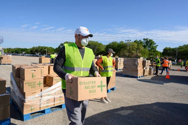 April 15, 2020, Austin, Texas, USA: Without fanfare, Texas head football coach Tom Herman volunteers putting 28-lb boxes of food into trunks of cars during a distribution drive that fed 2,500 Austin-area families on Wednesday. Texas is seeing a huge spike in food bank demand after job losses due to the coronavirus pandemic. Austin USA - ZUMAd150 20200415_znp_d150_046 Copyright: xBobxDaemmrichx