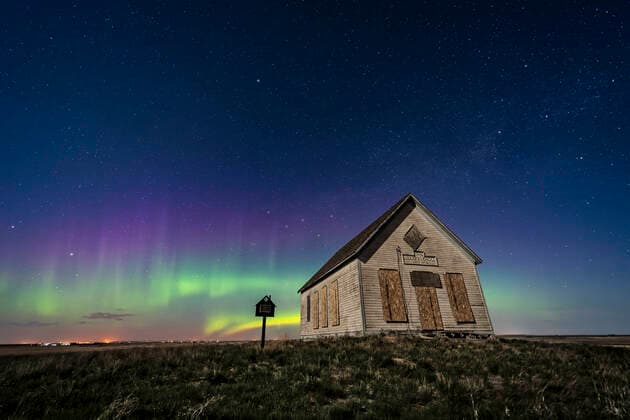 The 1910 Liberty Schoolhouse, a classic pioneer one-room school, on the Alberta prairie under the stars on a spring night, with an aurora dancing to the north. Moonlight provides the illumination. Cassiopeia is above the school. Polaris is at top. Copyright: AlanxDyer StocktrekxImages ADY200628S
