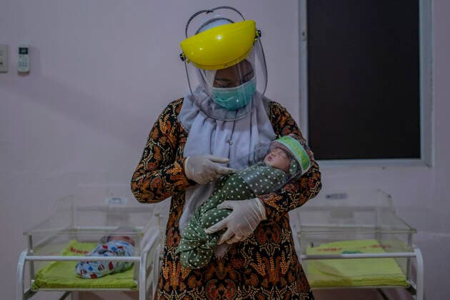 April 16, 2020, Bireuen, Aceh, Indonesia: A nurse wears a protective gear holds a newborn baby wearing a face shield as a protective measure amid fears of coronavirus disease COVID-19 at a hospital in Bireuen, Aceh province. Latest reports of COVID-19 cases, Indonesian confirms 5.516 positive cases, 548 recovered with 496 deaths. Bireuen Indonesia - ZUMAm250 20200416_zip_m250_008 Copyright: xZikrixMaulanax