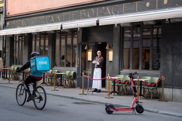A waiter looks out from a restaurant while a food delivery person passes by on his bicycle in Stockholm, Sweden April 17, 2020 STOCKHOLM Sweden x11610x,  Copyright: xStinaxStjernkvist TTx DAILY LIFE CORONA STOCKHOLM
