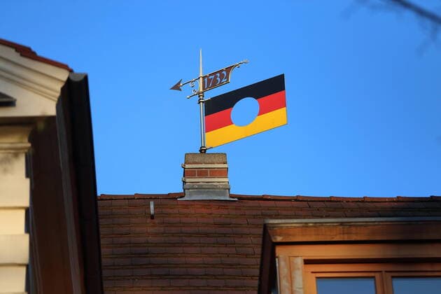 A Germany flag with a hole, the logo of the Federal Foundation for the Reappraisal of the SED dictatorship, serves as a weather vane on a house roof in Potsdam, 18 April 2020 Weather vane
