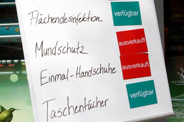 Sign with inscription mouthguard and disposable gloves sold out and surface disinfection and handkerchiefs available in front of a branch of the drugstore chain dm in the city center of Mannheim, Baden Württemberg, Germany