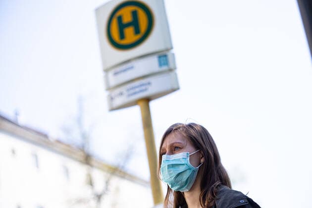 Masks mandatory in public transport in Berlin, People in Berlin will have to wear a mask in public transport from next week 27 April Public transport in buses, suburban trains and underground trains A young woman is standing at a bus stop with a mouth nose protection Berlin Berlin Germany